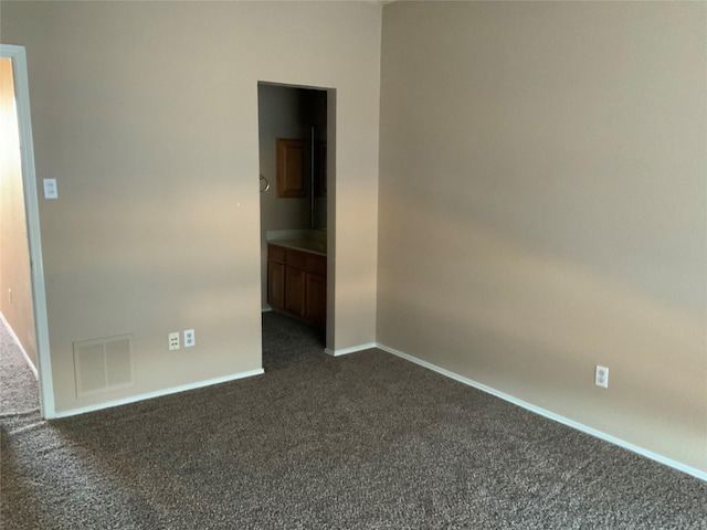 spare room with dark carpet