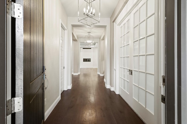 hall with dark hardwood / wood-style flooring and an inviting chandelier