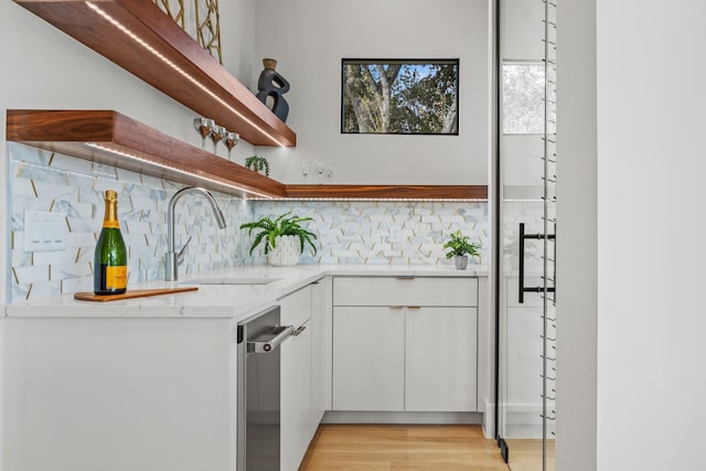 kitchen featuring white cabinetry, light hardwood / wood-style floors, sink, and backsplash