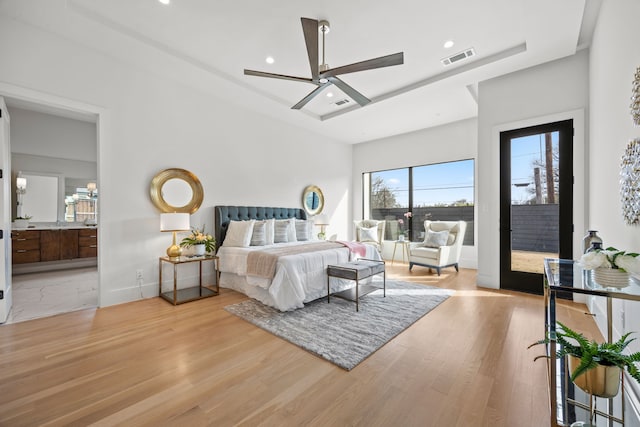 bedroom featuring a towering ceiling, connected bathroom, access to outside, ceiling fan, and light hardwood / wood-style flooring