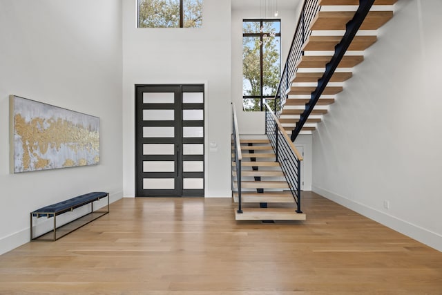 entrance foyer with a towering ceiling and light wood-type flooring