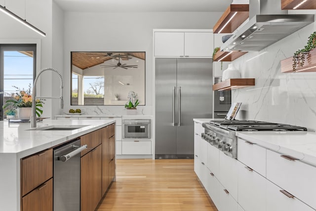 kitchen featuring light stone countertops, stainless steel appliances, white cabinets, and island exhaust hood