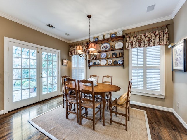 dining space with french doors, ornamental molding, dark hardwood / wood-style floors, and an inviting chandelier