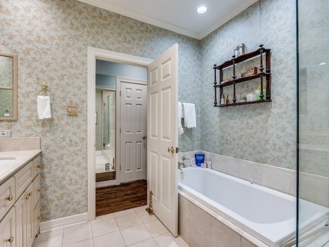 bathroom with ornamental molding, tile patterned floors, vanity, and tiled tub