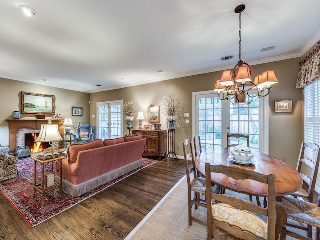 living room with crown molding, dark wood-type flooring, a chandelier, and french doors