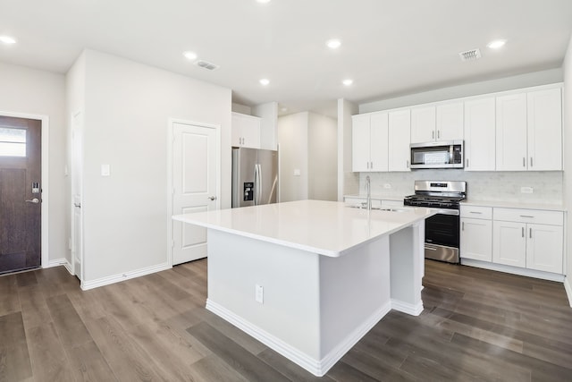 kitchen with white cabinetry, appliances with stainless steel finishes, sink, and a center island with sink