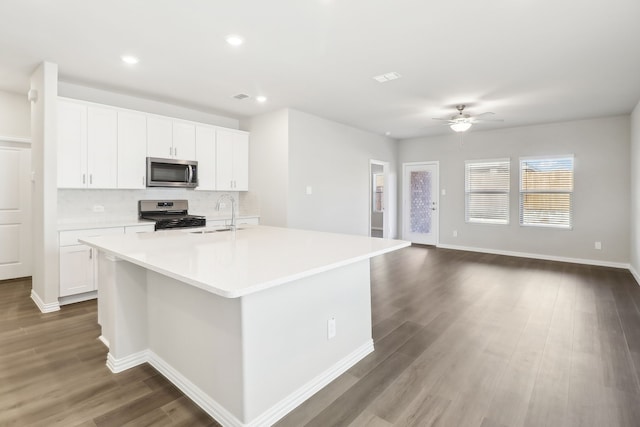 kitchen with sink, appliances with stainless steel finishes, a kitchen island with sink, white cabinetry, and decorative backsplash