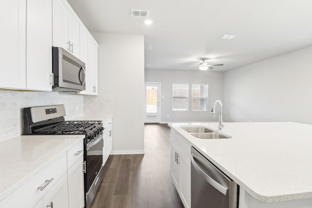 kitchen with sink, white cabinetry, appliances with stainless steel finishes, an island with sink, and backsplash