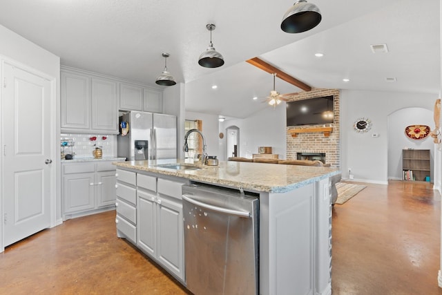 kitchen with appliances with stainless steel finishes, sink, a kitchen island with sink, and vaulted ceiling with beams