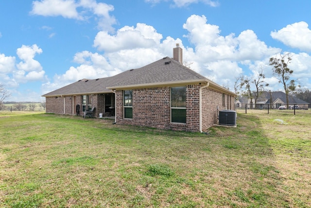 rear view of property with cooling unit and a lawn