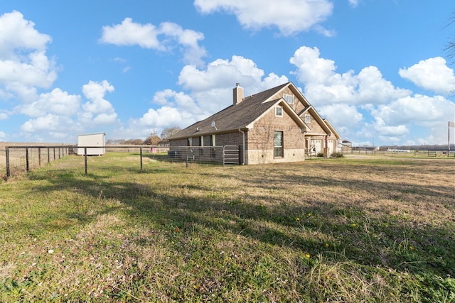 view of side of property with a rural view and a lawn