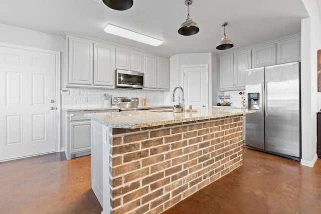 kitchen featuring light stone counters, sink, stainless steel appliances, and a center island with sink