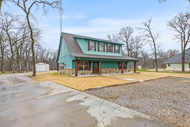 view of front of house featuring a garage, covered porch, and an outdoor structure