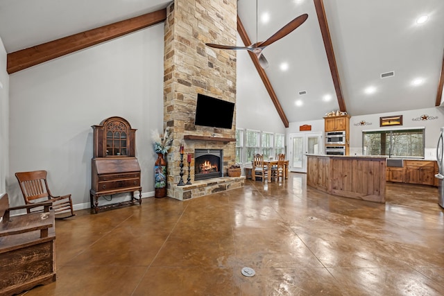 living room with beam ceiling, a stone fireplace, sink, ceiling fan, and high vaulted ceiling