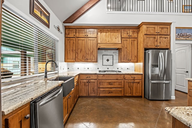 kitchen with appliances with stainless steel finishes, vaulted ceiling with beams, light stone countertops, backsplash, and sink