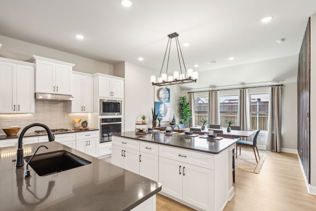 kitchen featuring white cabinetry, sink, stainless steel appliances, and hanging light fixtures