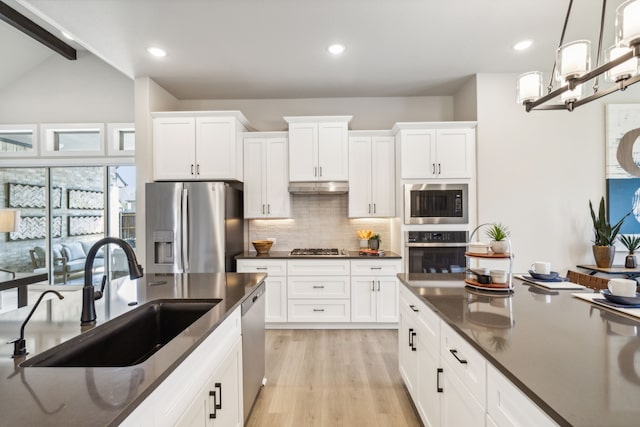 kitchen featuring stainless steel appliances, sink, pendant lighting, and white cabinets