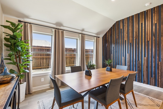 dining space featuring lofted ceiling and light hardwood / wood-style flooring