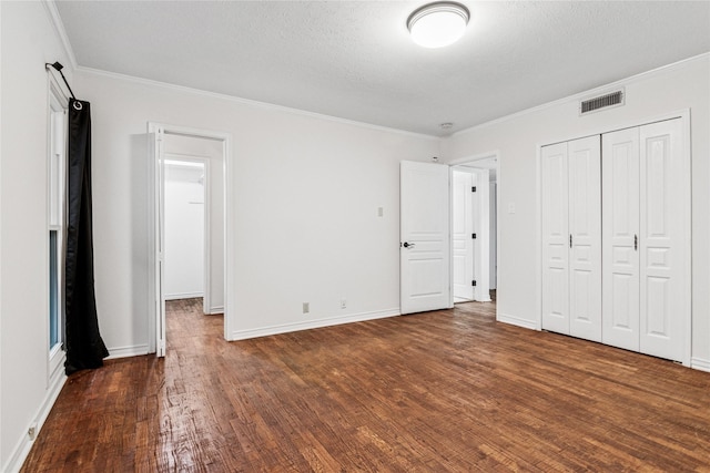 unfurnished bedroom with dark wood-type flooring, a closet, ornamental molding, and a textured ceiling