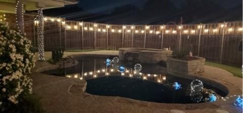 pool at twilight with a patio area and an in ground hot tub