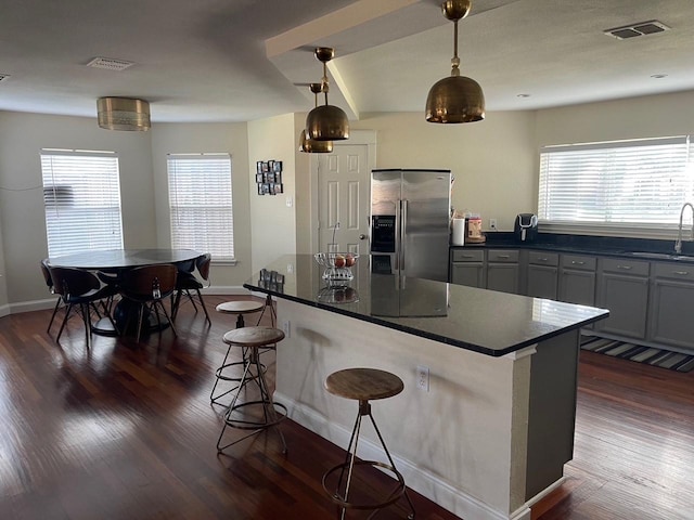 kitchen featuring sink, stainless steel fridge, a breakfast bar, dark hardwood / wood-style floors, and decorative light fixtures