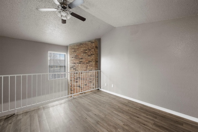 spare room featuring lofted ceiling, ceiling fan, wood-type flooring, and a textured ceiling