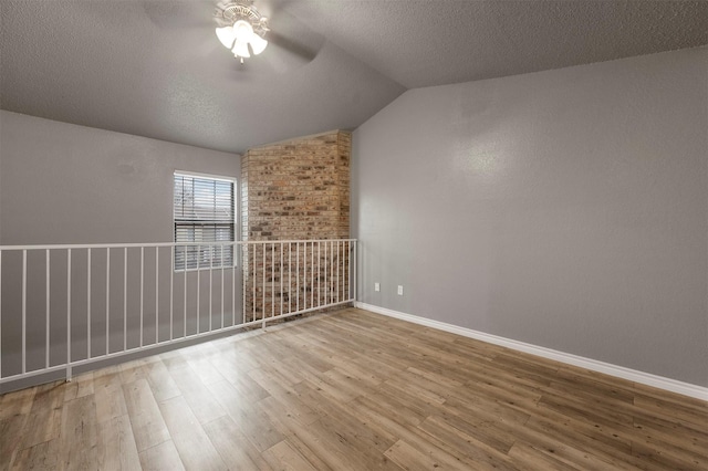 unfurnished room featuring ceiling fan, lofted ceiling, wood-type flooring, and a textured ceiling