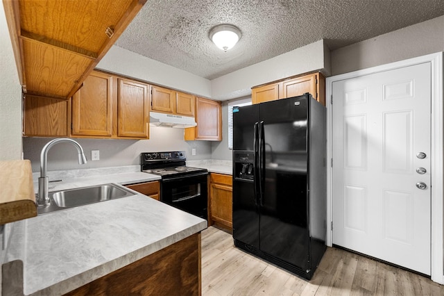 kitchen with sink, light hardwood / wood-style flooring, a textured ceiling, and black appliances