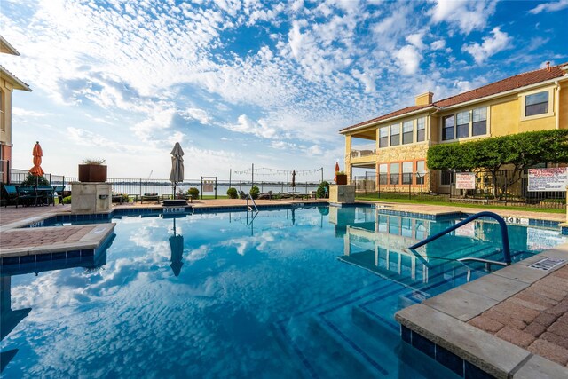 community pool with fence and a hot tub