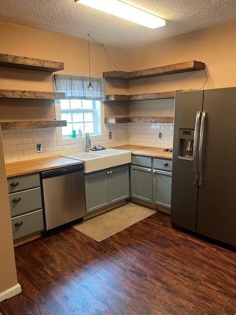 kitchen featuring appliances with stainless steel finishes, sink, backsplash, and dark hardwood / wood-style flooring