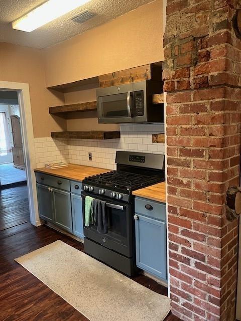 kitchen featuring gas stove, dark hardwood / wood-style floors, wooden counters, and backsplash