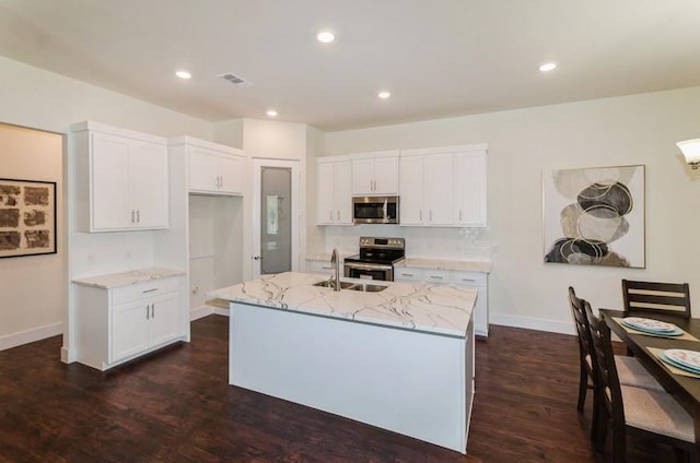 kitchen with light stone counters, appliances with stainless steel finishes, visible vents, and white cabinets