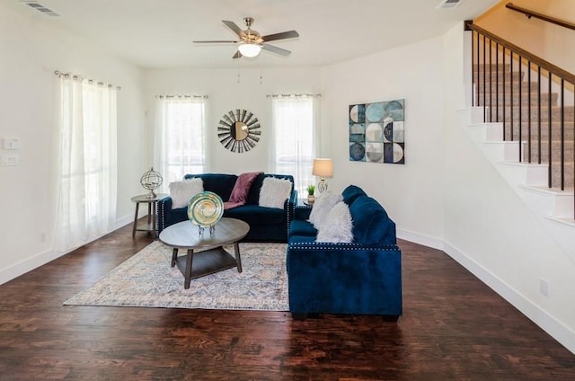 living room featuring stairs, visible vents, baseboards, and wood finished floors