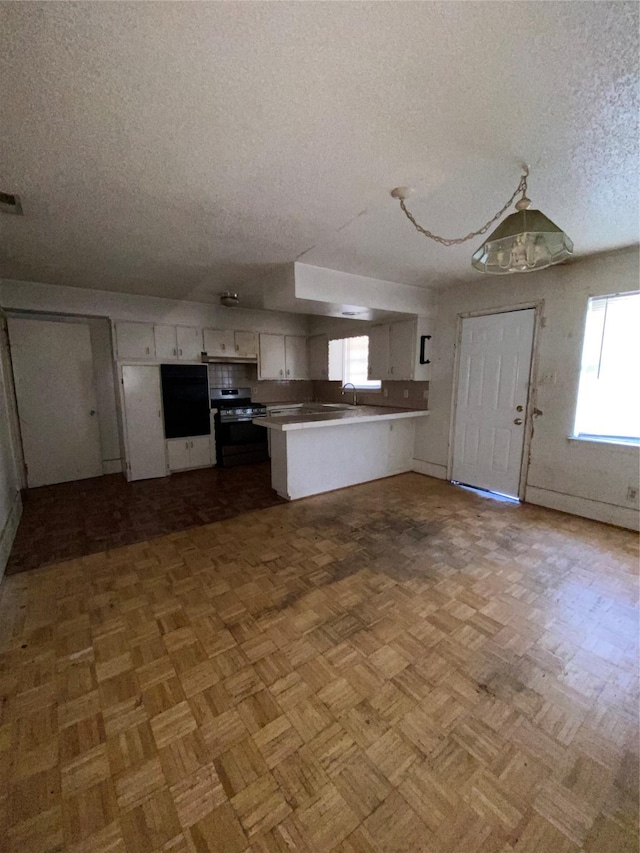 kitchen featuring sink, a textured ceiling, stainless steel range oven, white cabinets, and kitchen peninsula