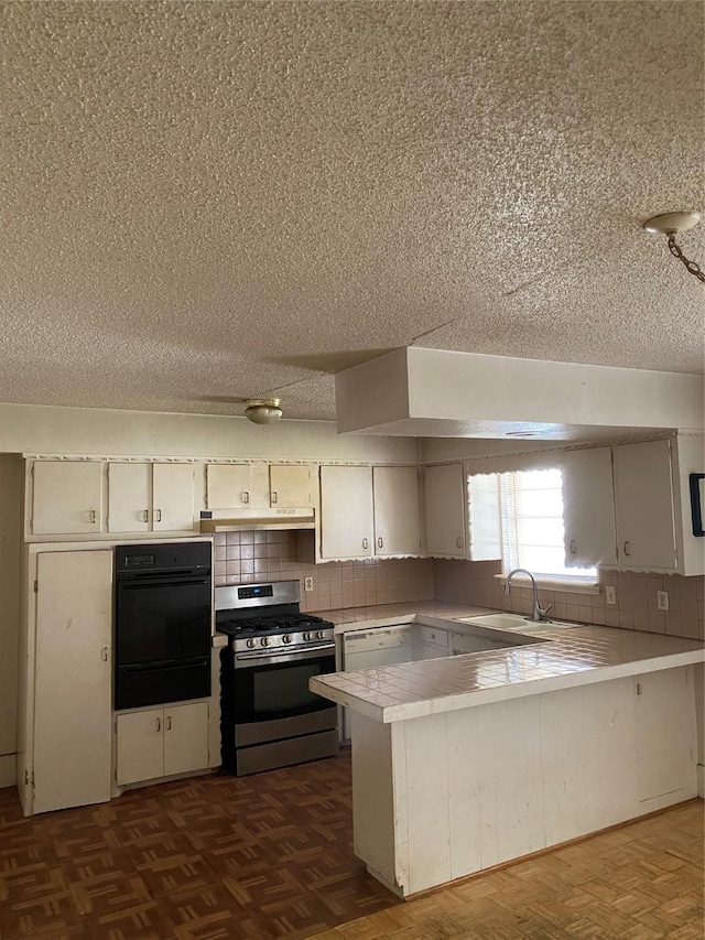 kitchen featuring gas stove, sink, dark parquet floors, and kitchen peninsula