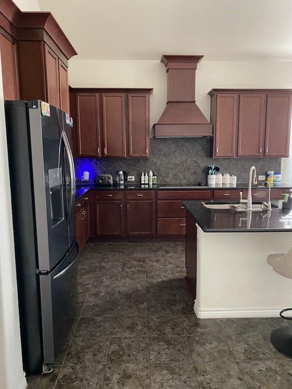 kitchen with premium range hood, sink, decorative backsplash, black electric stovetop, and stainless steel refrigerator with ice dispenser