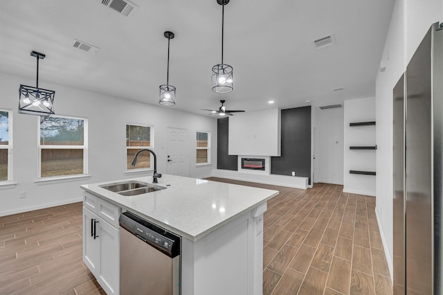 kitchen featuring pendant lighting, sink, appliances with stainless steel finishes, white cabinetry, and a kitchen island with sink