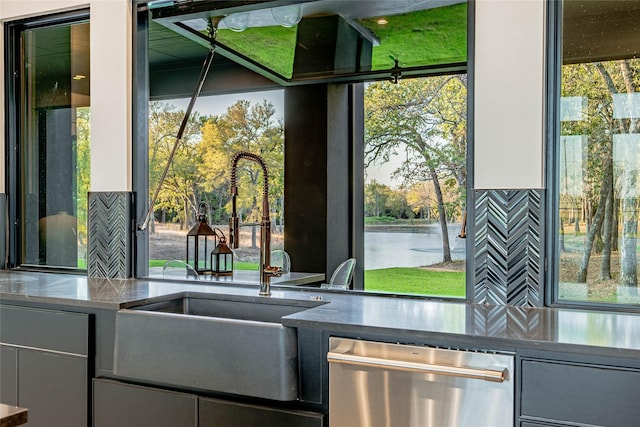 interior space with dishwasher, a water view, sink, and backsplash