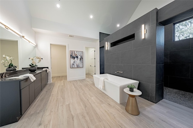 bathroom with hardwood / wood-style flooring, vanity, tile walls, and plus walk in shower