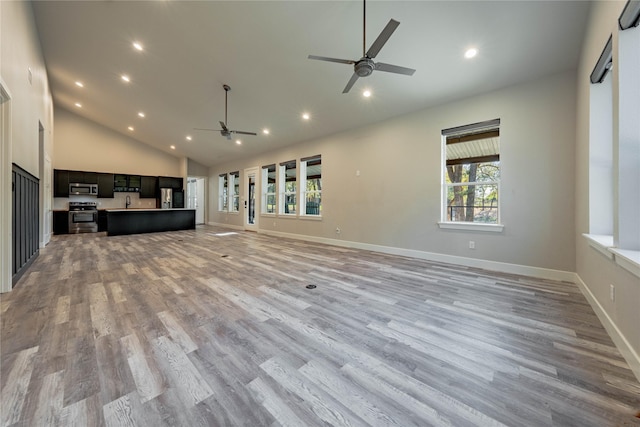 unfurnished living room with plenty of natural light, high vaulted ceiling, ceiling fan, and light wood-type flooring