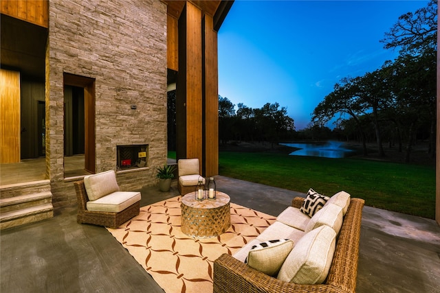 patio terrace at dusk with a yard and an outdoor stone fireplace