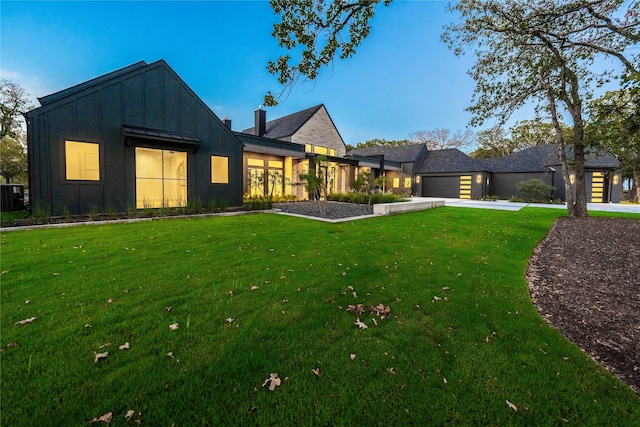 view of front of house with cooling unit, a garage, and a front lawn