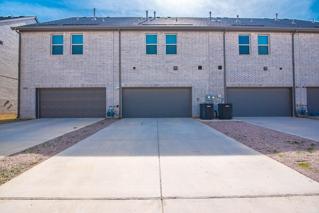 rear view of property featuring a garage and central air condition unit