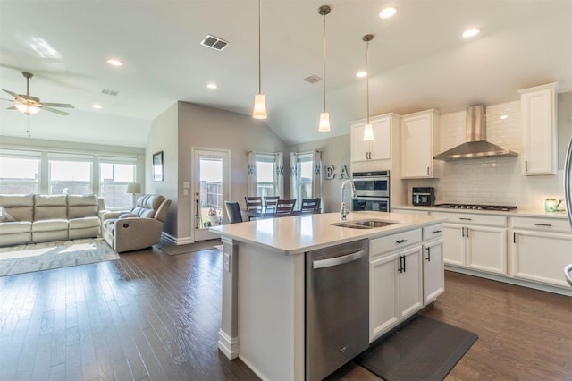 kitchen with white cabinetry, hanging light fixtures, stainless steel appliances, an island with sink, and wall chimney exhaust hood