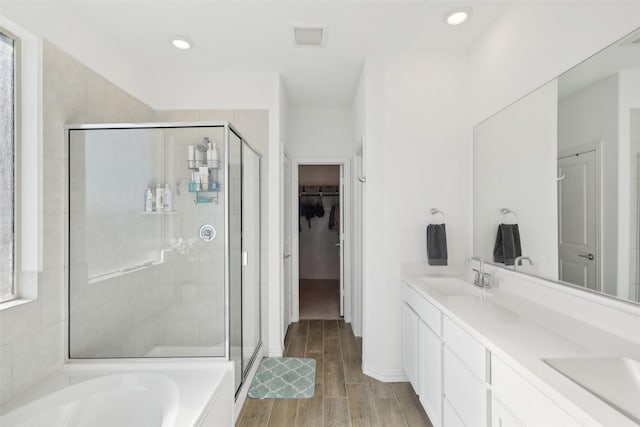 bathroom featuring a spacious closet, visible vents, wood tiled floor, a stall shower, and a sink