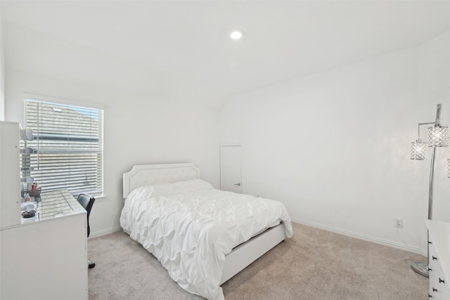 bedroom featuring baseboards, light colored carpet, and lofted ceiling