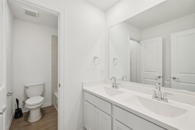 full bathroom with a sink, visible vents, toilet, and wood finished floors