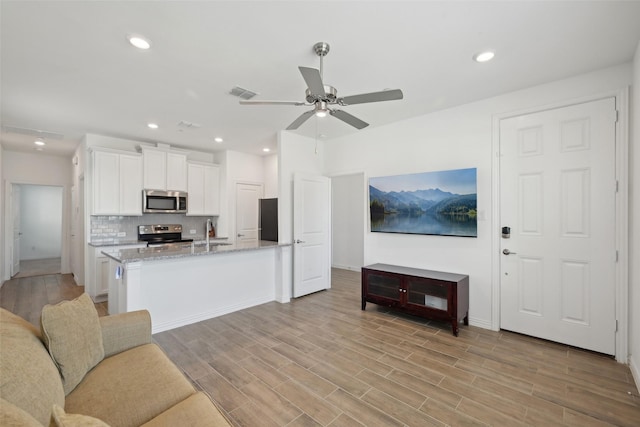 kitchen featuring visible vents, a sink, decorative backsplash, stainless steel appliances, and white cabinetry