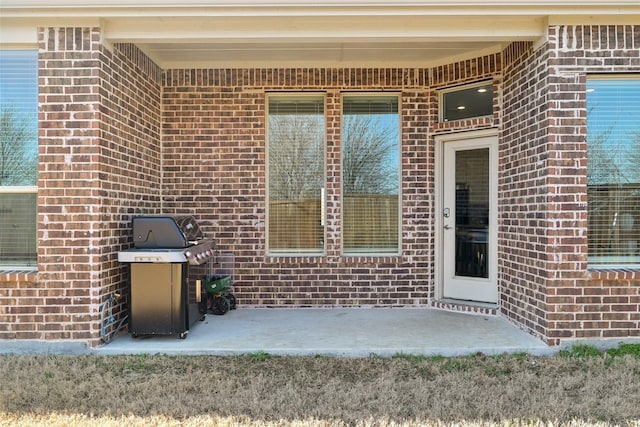 property entrance featuring a patio and brick siding