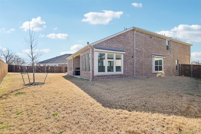 back of property featuring a fenced backyard, brick siding, and a lawn